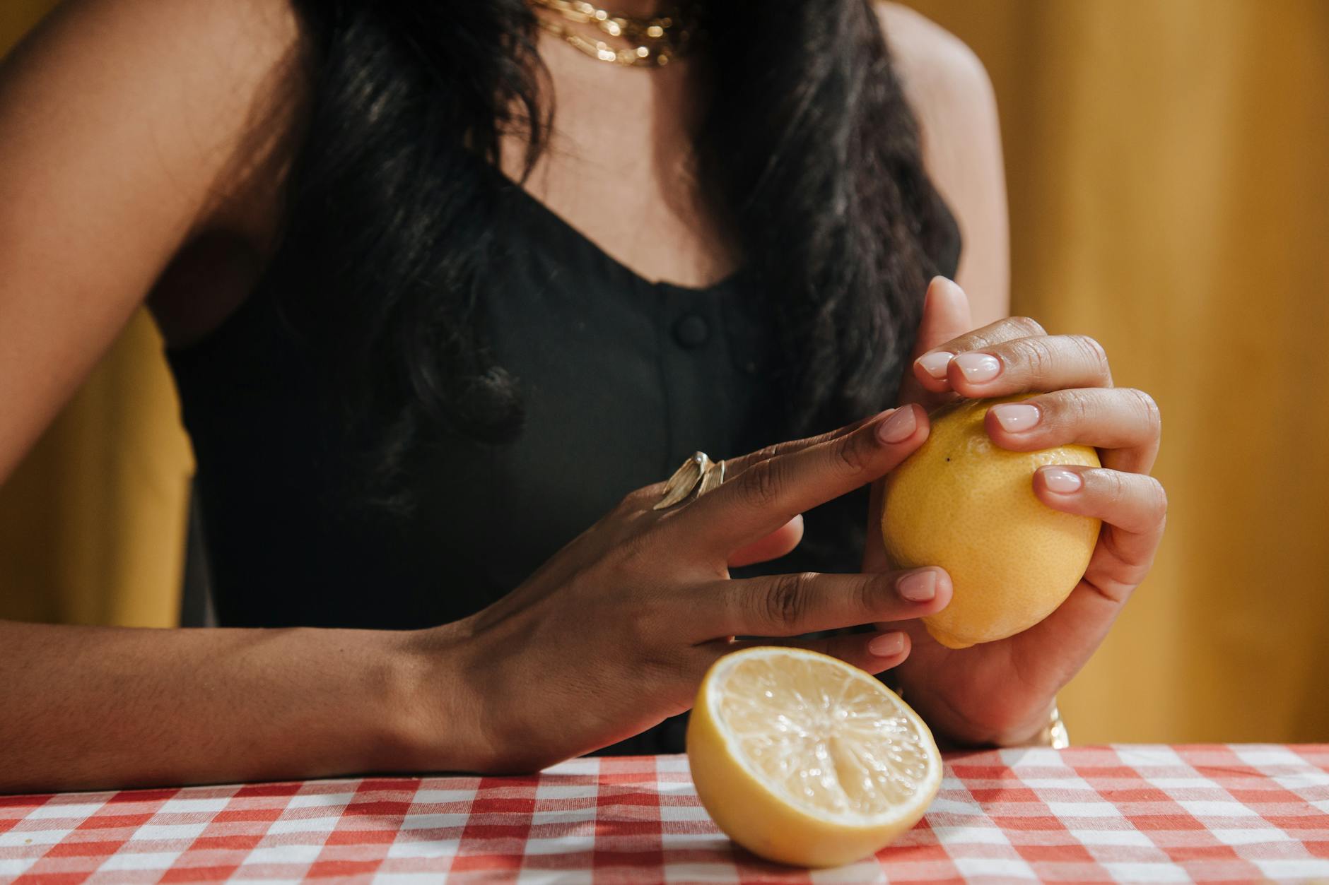 Mulher segurando limão fresco em uma mesa de jantar