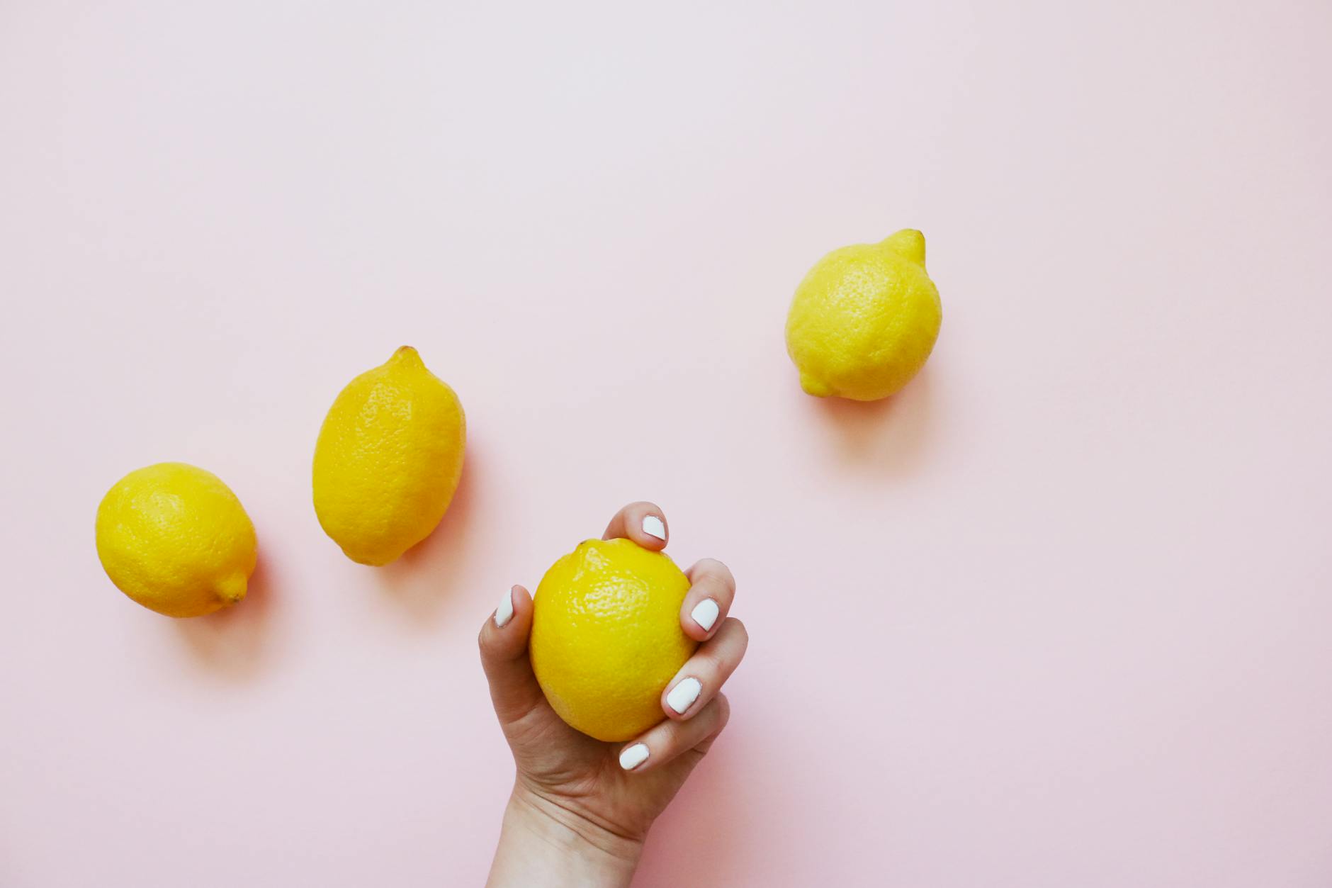Uma mão segurando um limão em fundo rosa suave, simbolizando frescor e renovação sexual