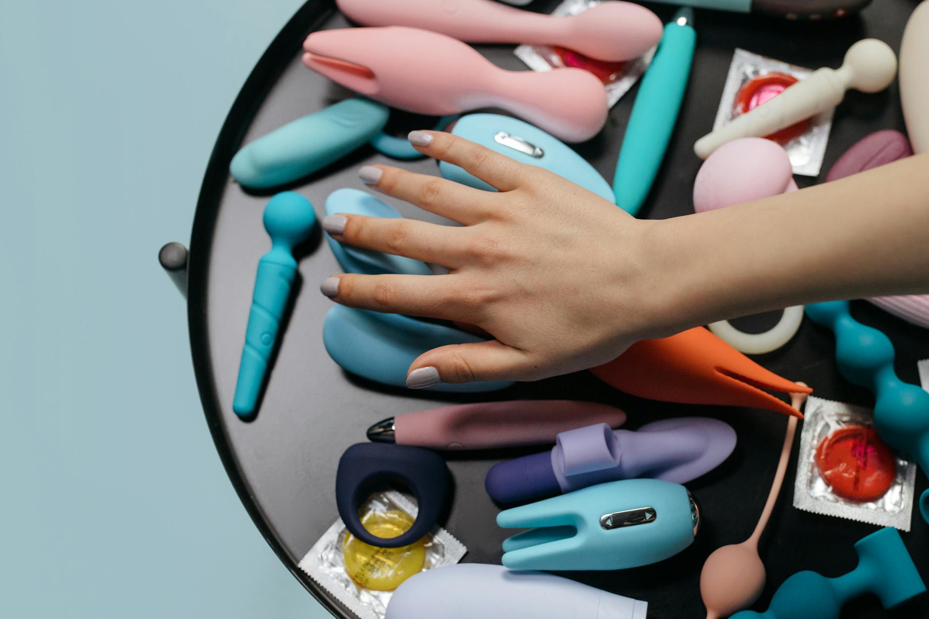 Mão com unhas brancas segurando um limão em fundo rosa suave, cercada por três limões adicionais