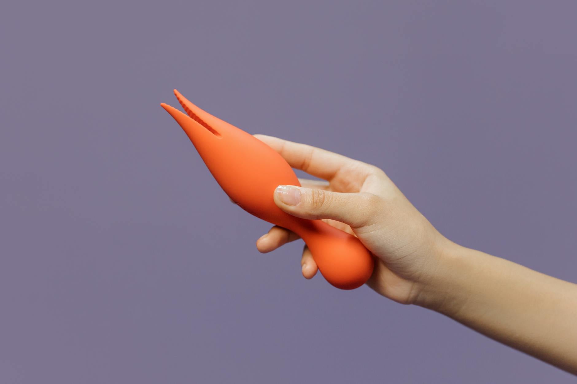 Mão segurando um vibrador de limão contra um fundo roxo minimalista, mostrando sensualidade moderna.
