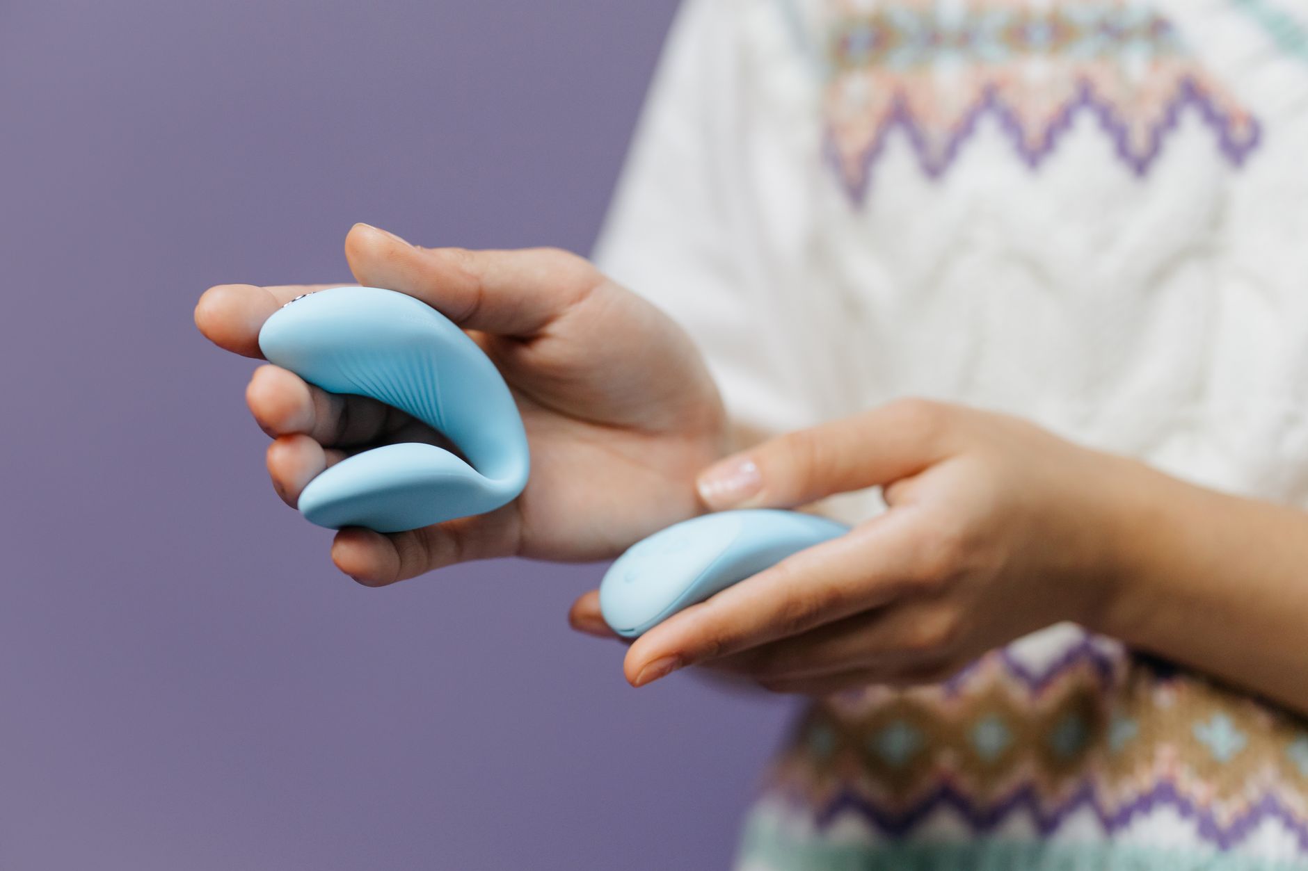 Mão segurando um vibrador de limão azul elegante sobre fundo roxo suave
