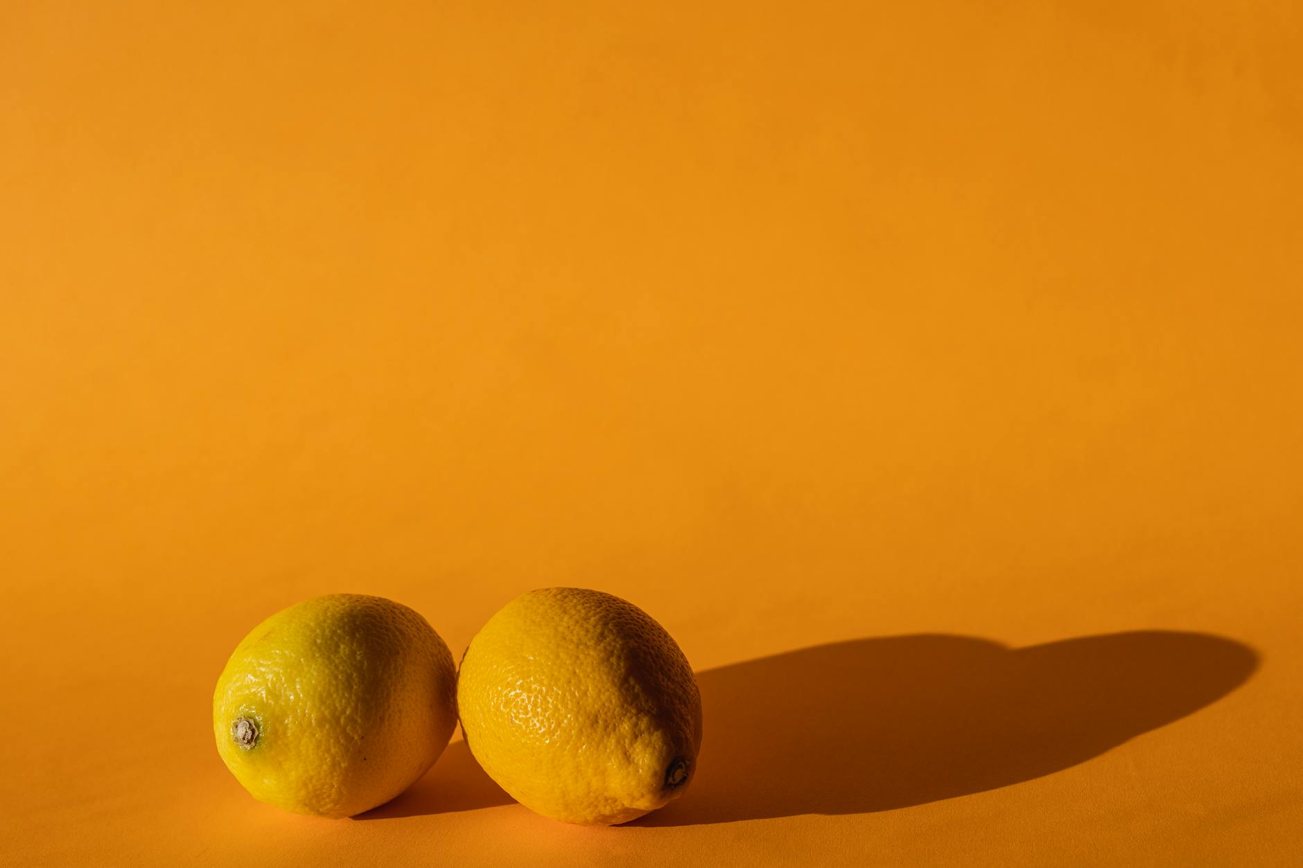 Vibrador azul cercado por flores e frutas cítricas em fundo amarelo brilhante